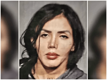 A person with long dark hair, wearing a gray top, looking at the camera with a neutral expression against a plain background.