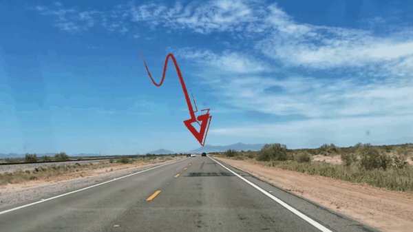A red arrow points to a distant car on a straight, empty desert highway under a blue sky with scattered clouds.