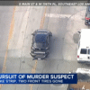 A damaged black car is pursued by police vehicles on a street as news text reports an LAPD chase of a murder suspect with blown front tires in Southeast Los Angeles.