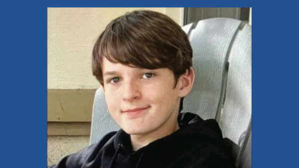 A young boy with brown hair and a black hoodie sits on a chair and smiles. Above him, large white text reads "MISSING PERSONS" on a blue background.